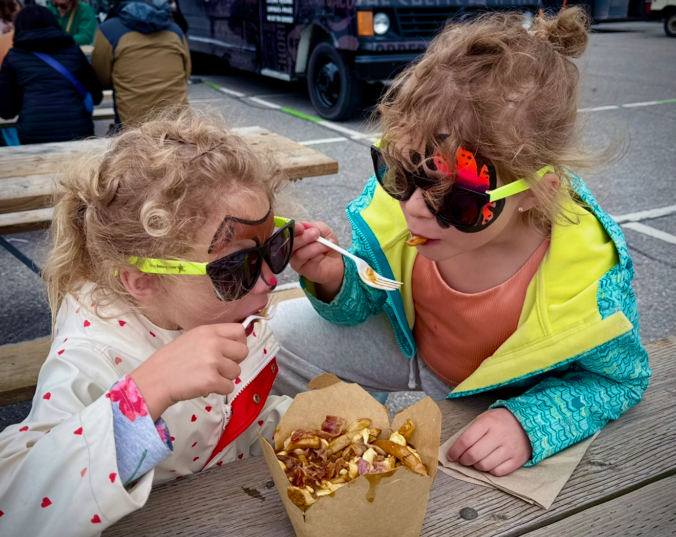Two little girls sharing a pouting wearing sunglasses at Food Truck Frenzy Whitby 2025