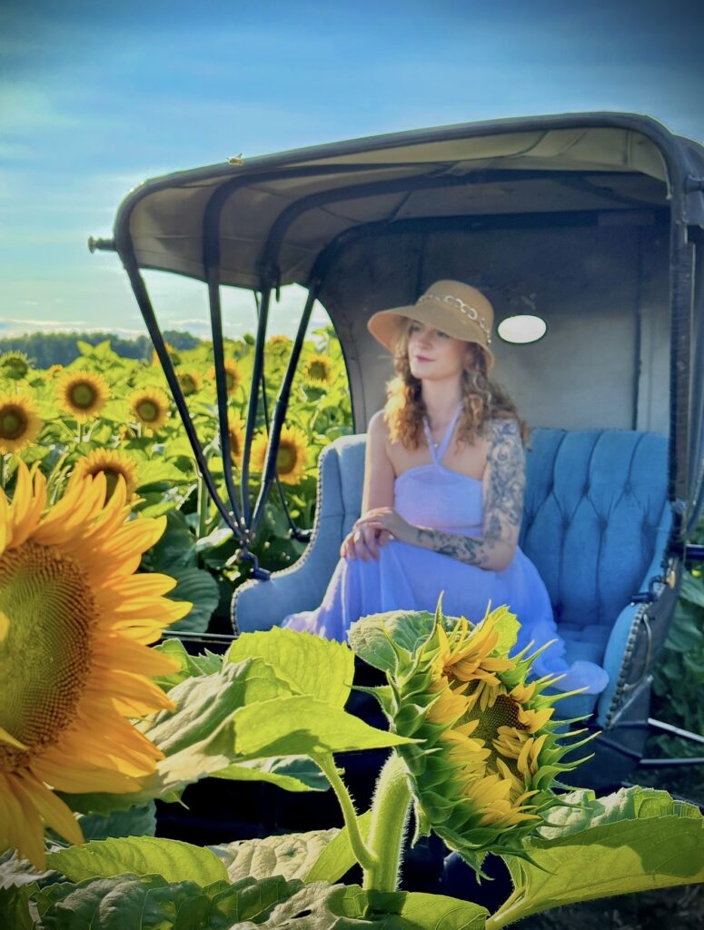 Girl poses in an antique horse carriage prop in the middle of a sunflower field at Bragg Farms in Bowmanville