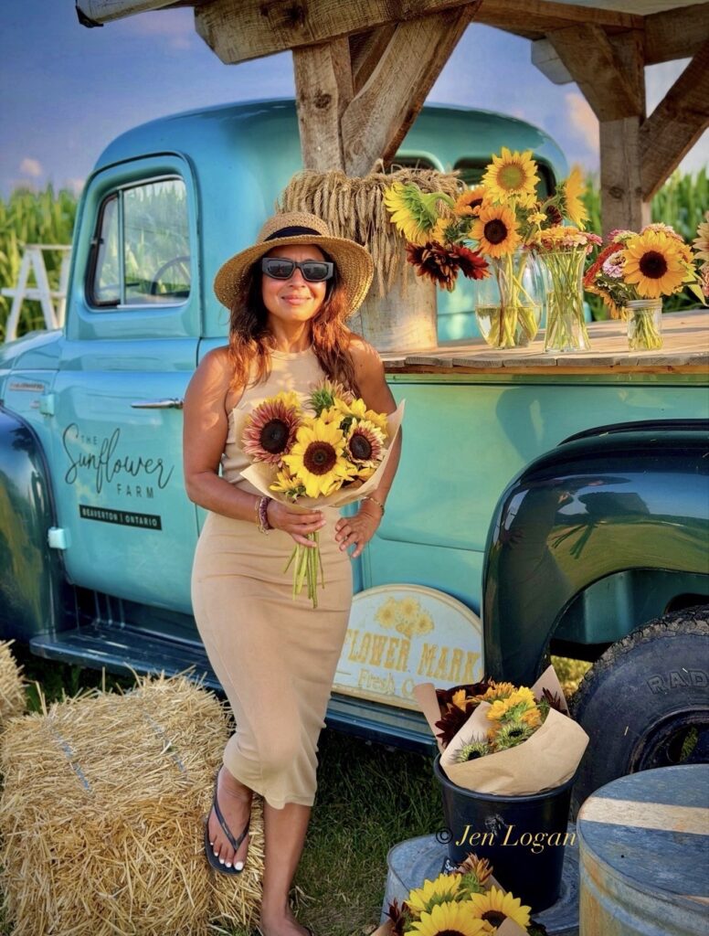 Woman posing in front of an old redone 1920's era baby blue pickup truck with sunflower bouquets at the Sunflower Farm in Beaverton